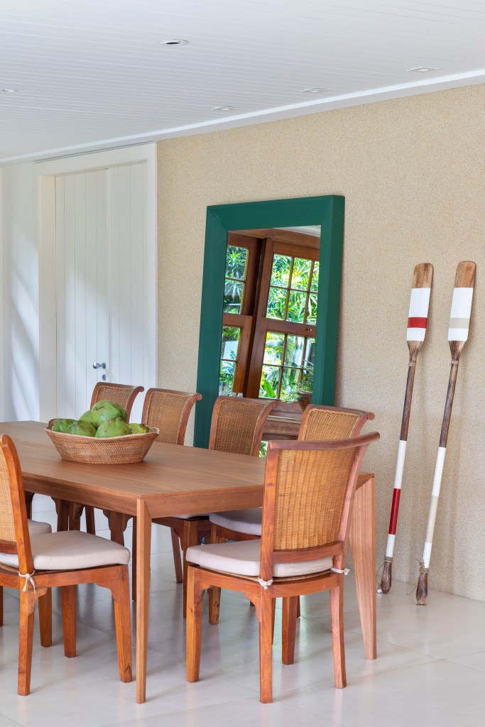 Sala de jantar com mesa e cadeiras de madeira e espelho de piso.