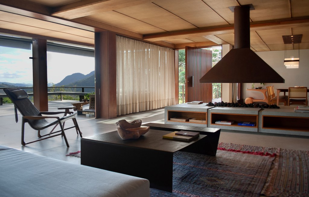 Sala de estar integrada com lareira e painéis de madeira.