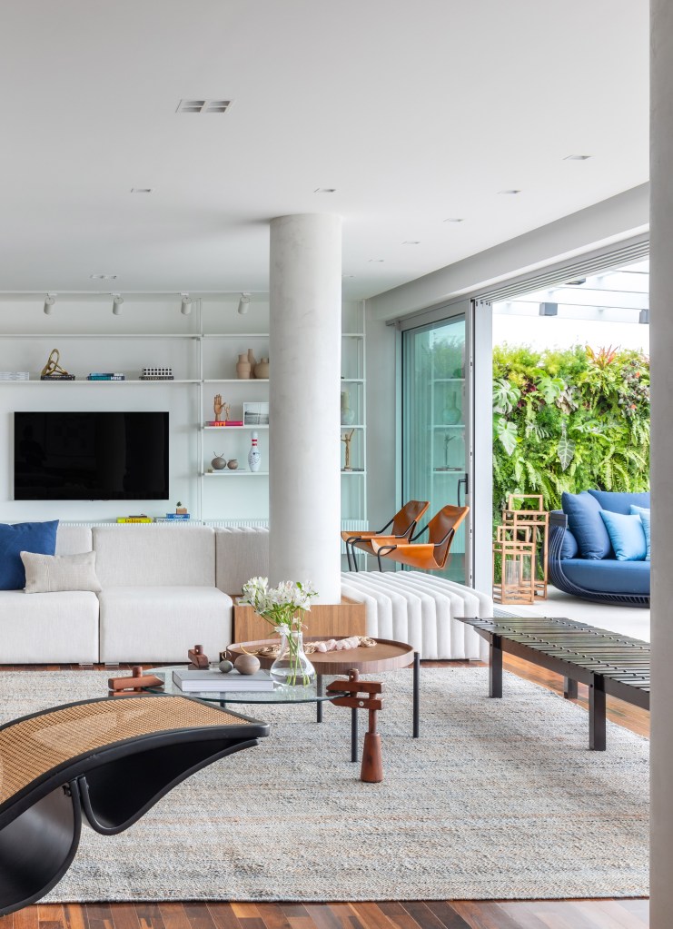 Sala de estar clara com móveis de design brasileiro e piso de madeira.