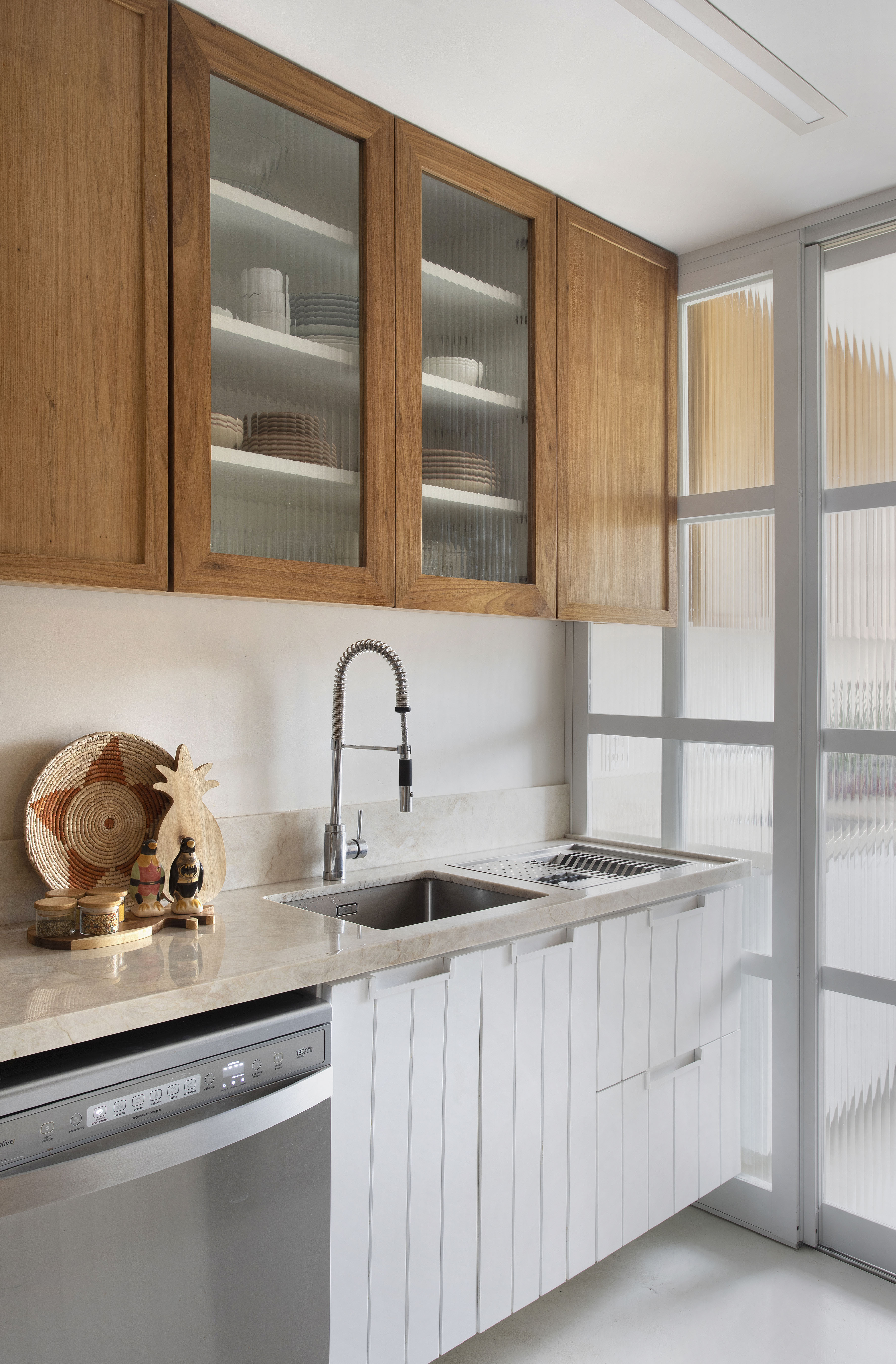 Cozinha clara com armários em marcenaria e portas de vidro.