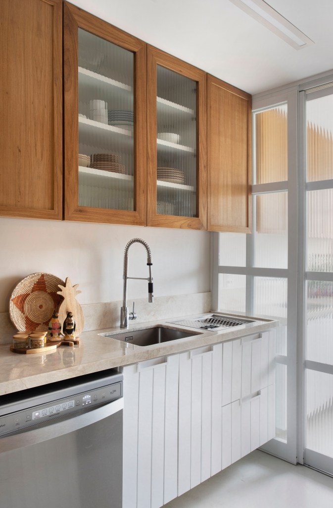 Cozinha clara com armários em marcenaria e portas de vidro.