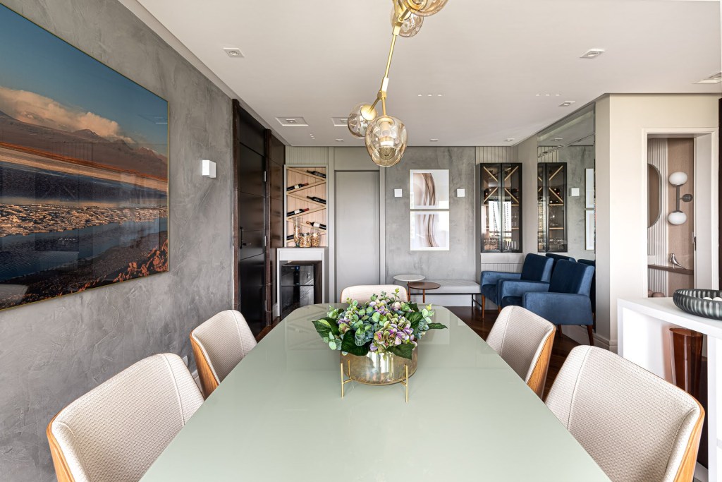 Estilo contemporâneo e industrial marca o décor deste apartamento de 110 m². Projeto Estúdio Wall Arquitetura. Na foto, sala de jantar integrada com quadro na parede de cimento queimado, espelhos e adega.