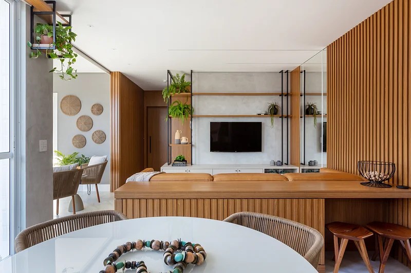 Sala integrada com painel de madeira, buffet de madeira e mesa redonda.
