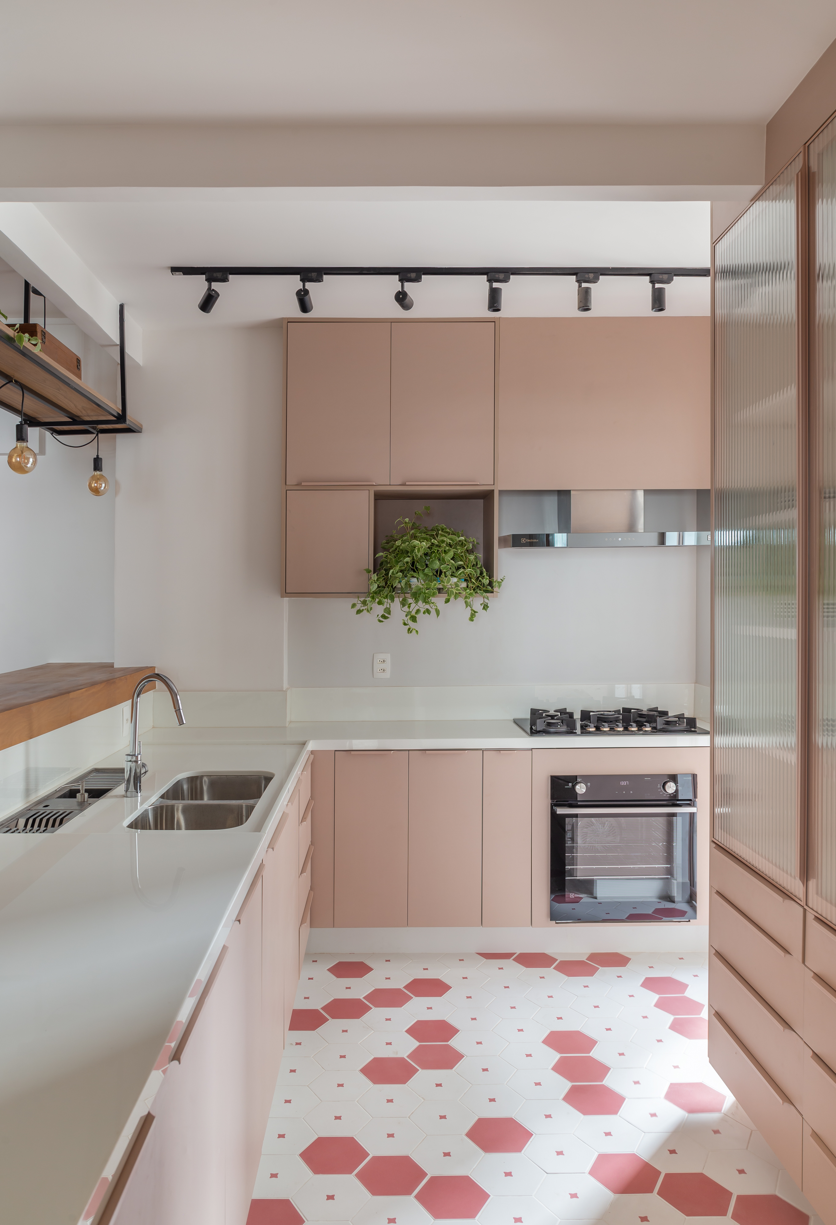 Cozinha com marcenaria rosa, bancada branca e piso em ladrilho hidráulico.