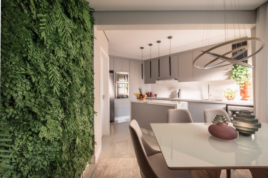 Sala de jantar integrada com cozinha e jardim vertical com plantas preservadas.