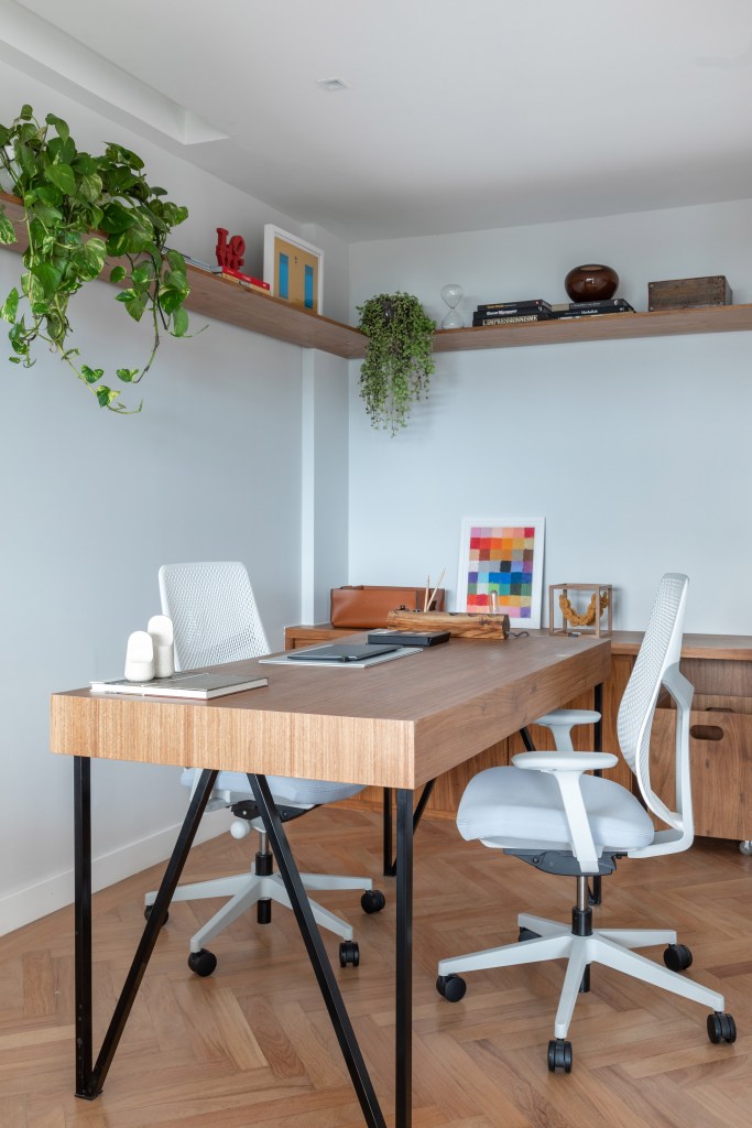 Home office com mesa de madeira e cadeiras de escritório brancas.