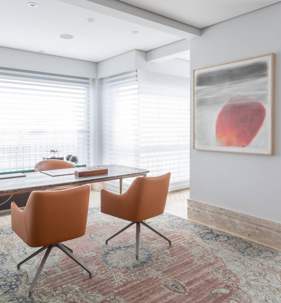 Home office com poltronas em tons terrosos e tapete.