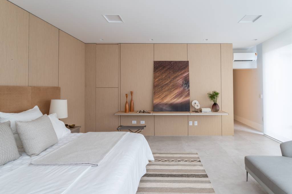 Quarto com cama de casal, tapete listrado e paleta em tons terrosos.