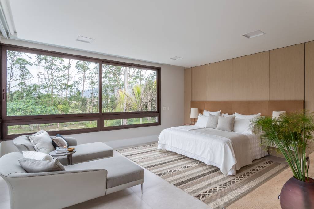 Quarto amplo com cama de casal e paleta de tons terrosos.