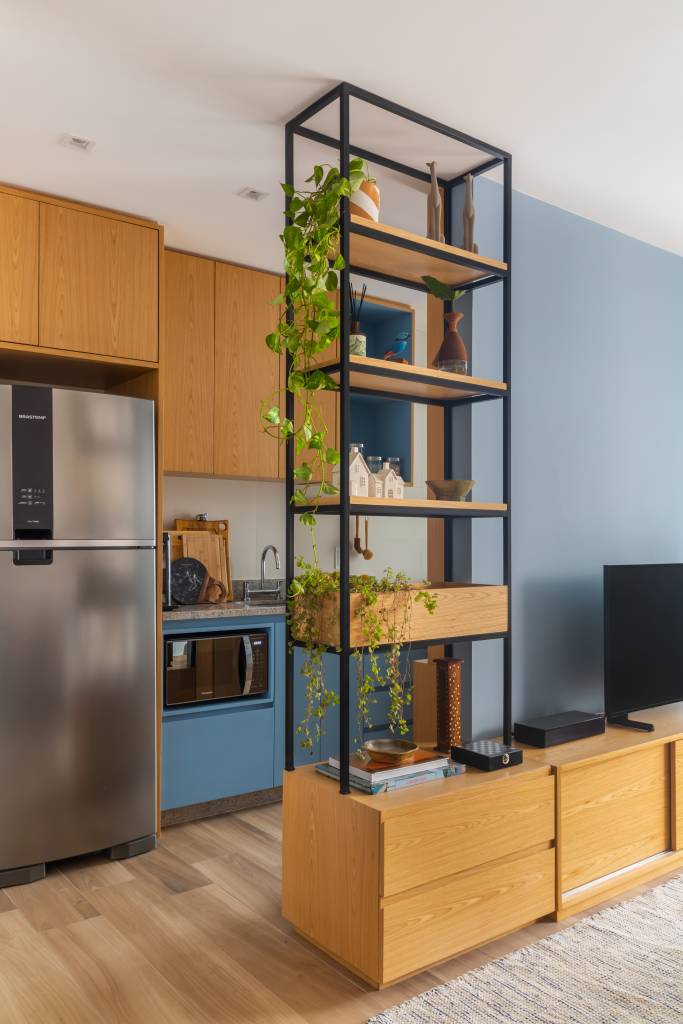 Sala com estante vazada e cozinha.