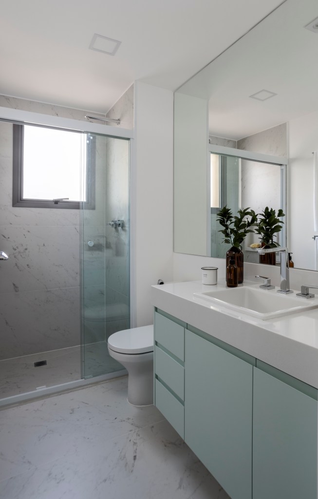 Apê de 110 m² com pé-direito duplo vira duplex com mezanino metálico. Na foto, banheiro com marcenaria verde.
