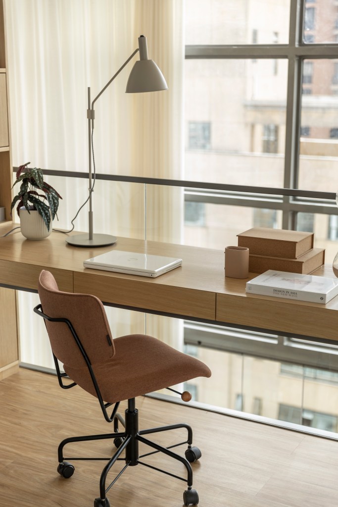 Apê de 110 m² com pé-direito duplo vira duplex com mezanino metálico. Na foto, mezanino com home office e vista para a janela.