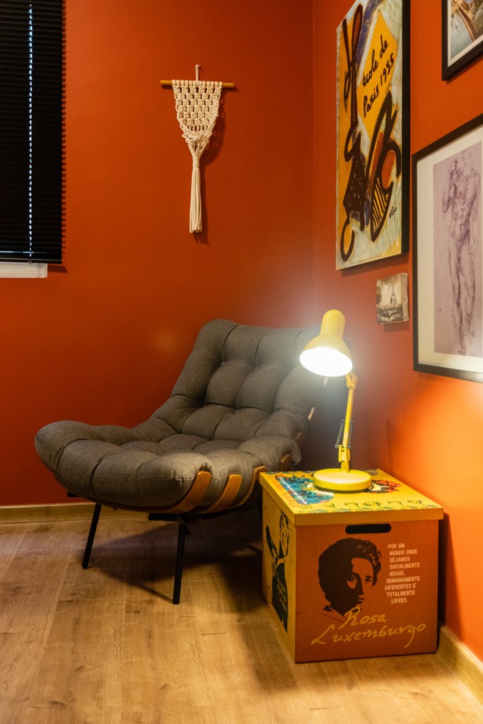 Home office; cantinho de leitura com parede vermelha e poltrona costela cinza.