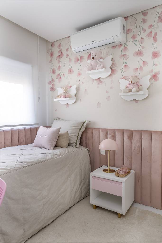 Quarto infantil de menina com papel de parede de flores e cabeceira acolchoada rosa.