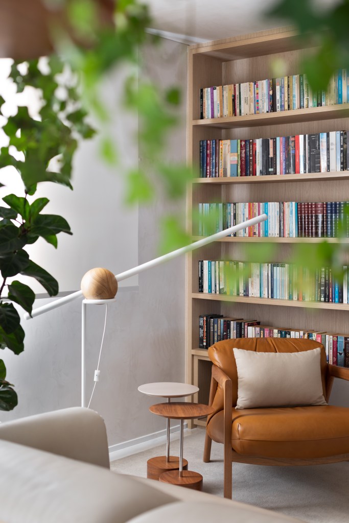 Dicas fáceis para montar um cantinho da leitura em casa. Cantinho de leitura com poltrona de couro, luminária de piso e estante de livros.
