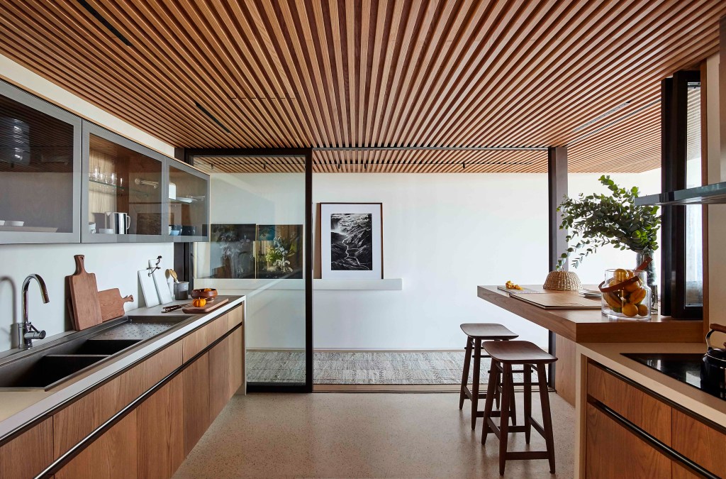 Cozinha integrada com revestimentos de madeira, teto de madeira ripada.