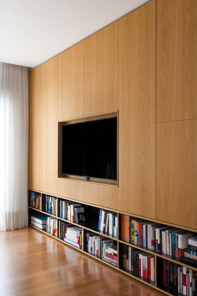 Painel de madeira para tv com abertura baixa para livros.