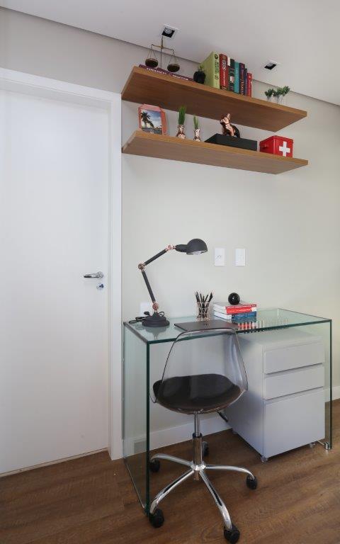 Home office pequeno com mesa pequena de vidro.