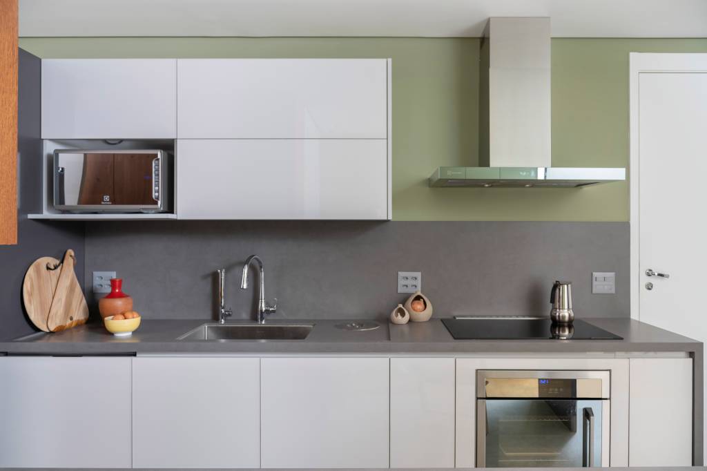 bancada-de-cozinha-materiais-vantagens-desvantagens-raizes-arquitetos-01 Cozinha com bancada de Neolith, marcenaria branca e parede verde.
