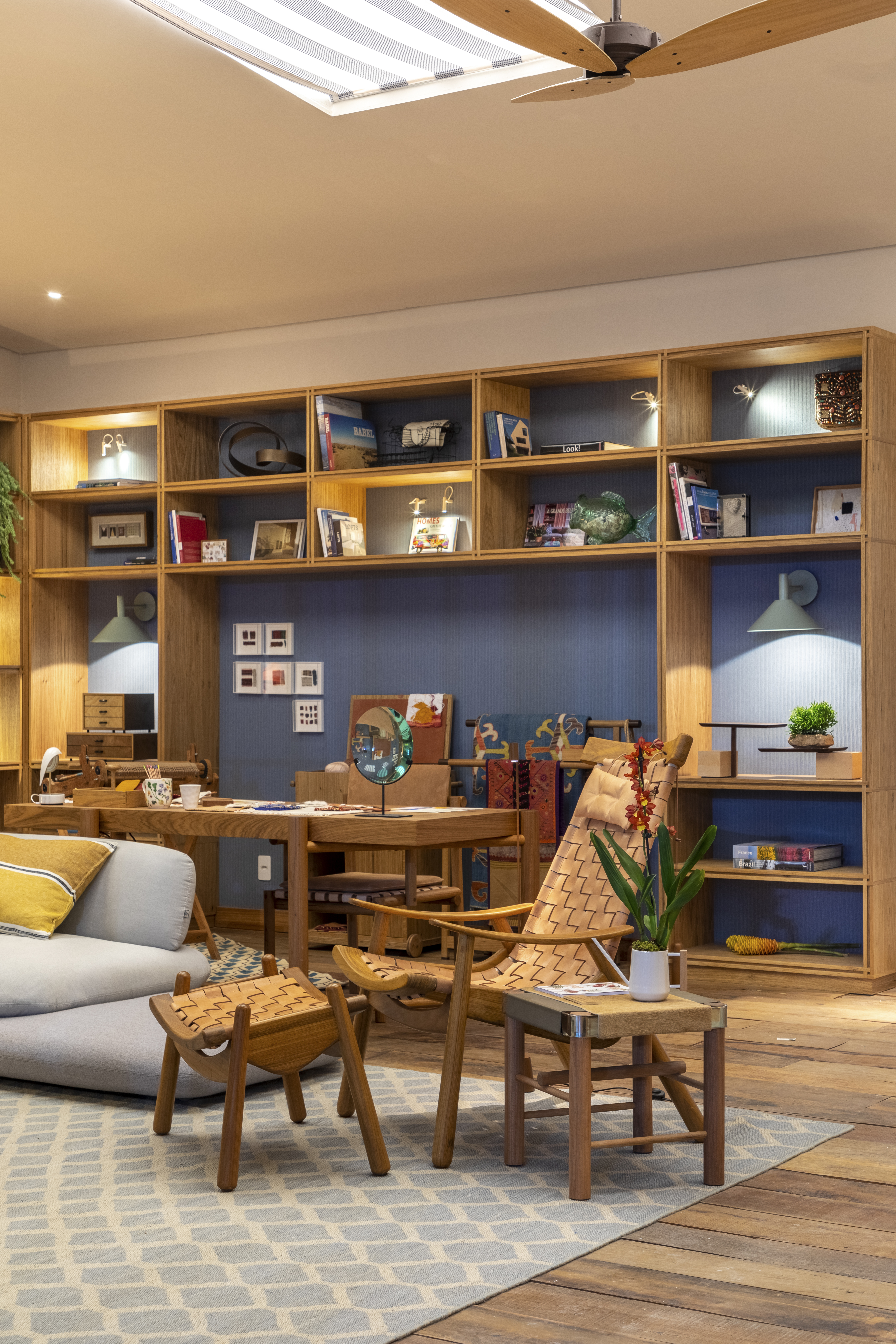 Sala de estar com estante de madeira com nichos, parede azul e sofá.