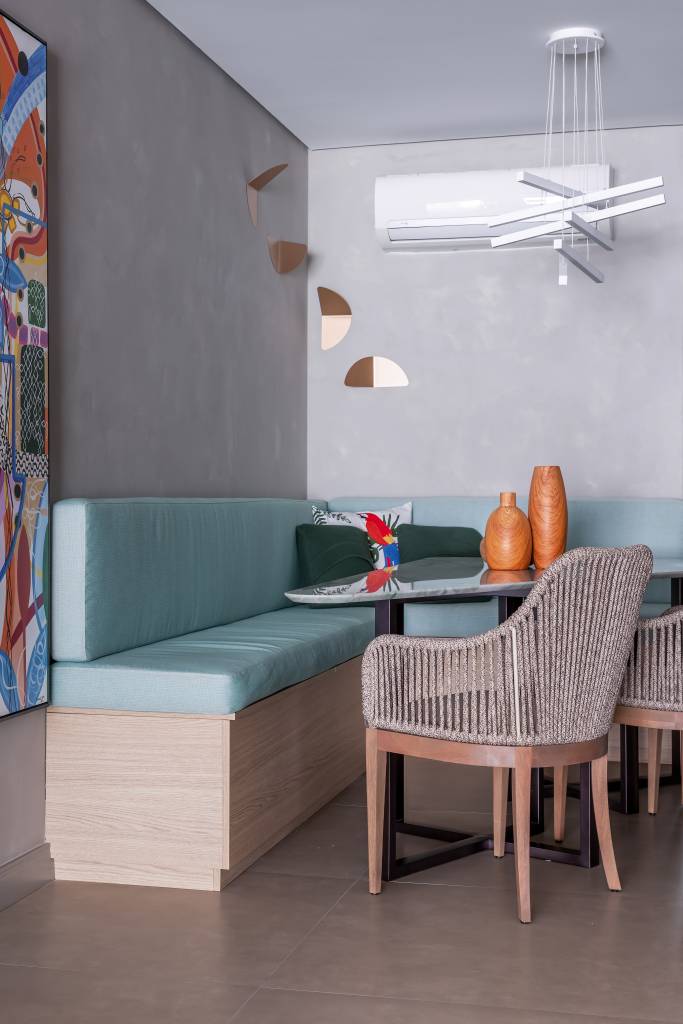 Sala de jantar com parede cinza e canto alemão com almofadas azuis.