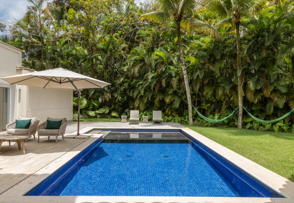 Casa no Guarujá de 600 m² tem jardim tropical e piscina com prainha. Projeto Stal Arquitetura. Na foto, piscina com varanda e jardim.