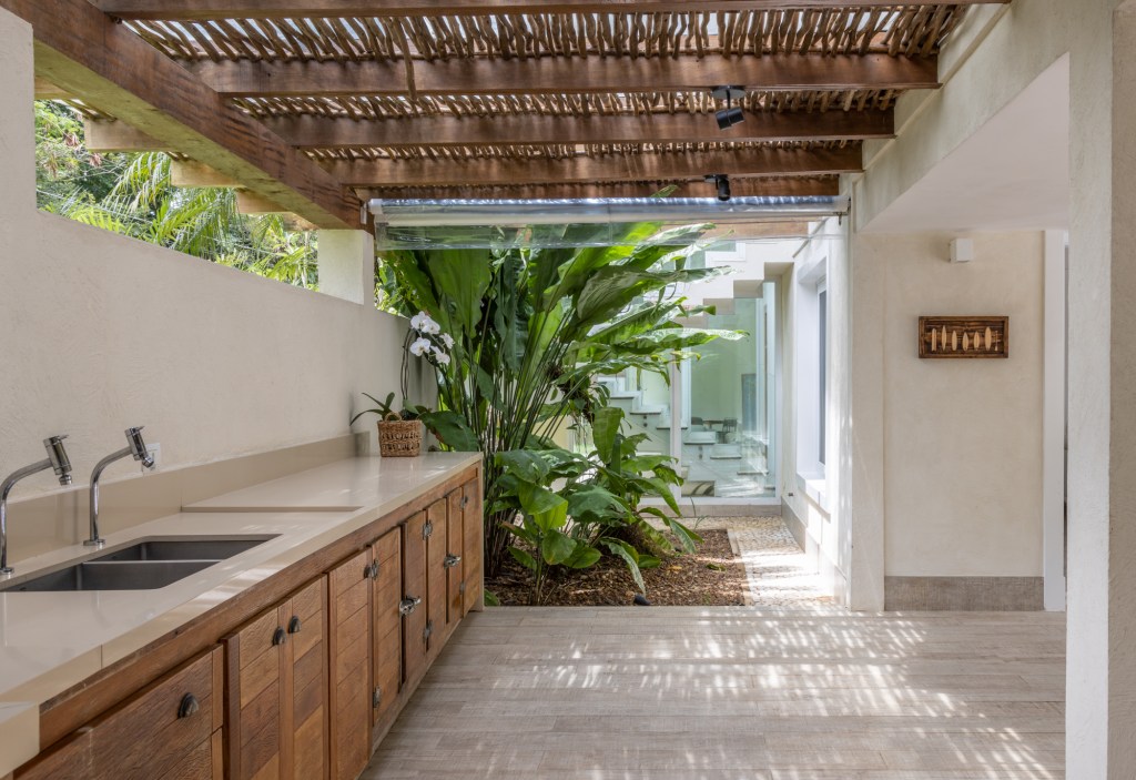 Casa no Guarujá de 600 m² tem jardim tropical e piscina com prainha. Projeto Stal Arquitetura. Na foto, varanda com pergolado e espaço gourmet.