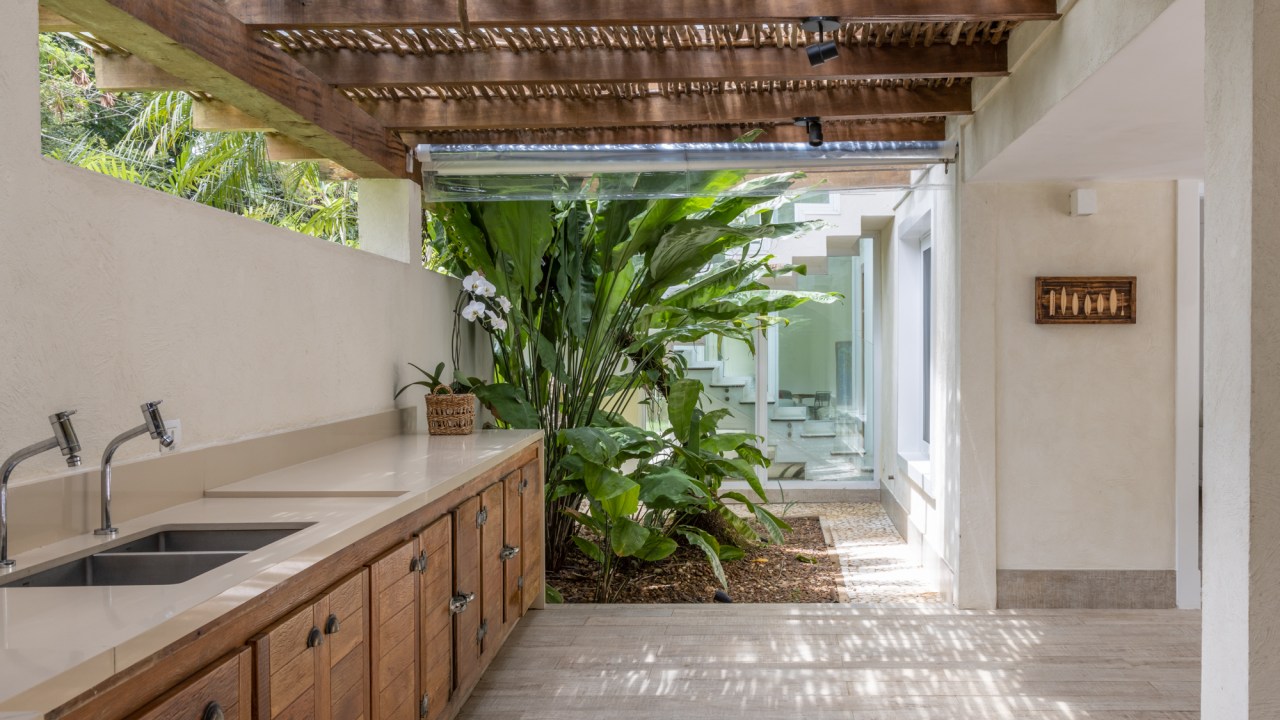 Casa no Guarujá de 600 m² tem jardim tropical e piscina com prainha. Projeto Stal Arquitetura. Na foto, varanda com pergolado e espaço gourmet.