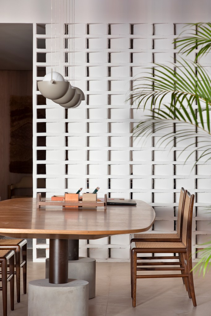 Casa que abraça: um projeto cozy, colorido e com clima carioca. Projeto de Migs Arquitetura na CASACOR SP 2023. Na foto, sala de jantar com parede de cobogós e mesa de madeira.