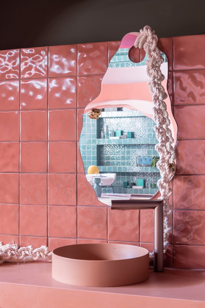 Casa rosa de 225 m² com cara de brinquedo feita para moradora de 64 anos. Projeto de Ricardo Abreu para a CASACOR SP 2023. Na foto, banheiro com espelho orgânico e cuba rosa.