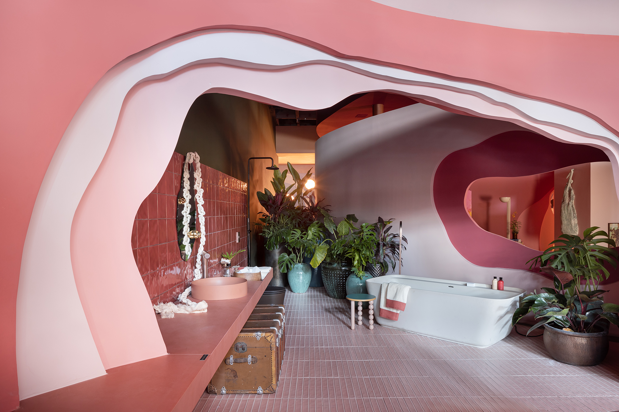 Casa rosa de 225 m² com cara de brinquedo feita para moradora de 64 anos. Projeto de Ricardo Abreu para a CASACOR SP 2023. Na foto, banheiro com bancada e cuba rosa. Banheira de apoio.