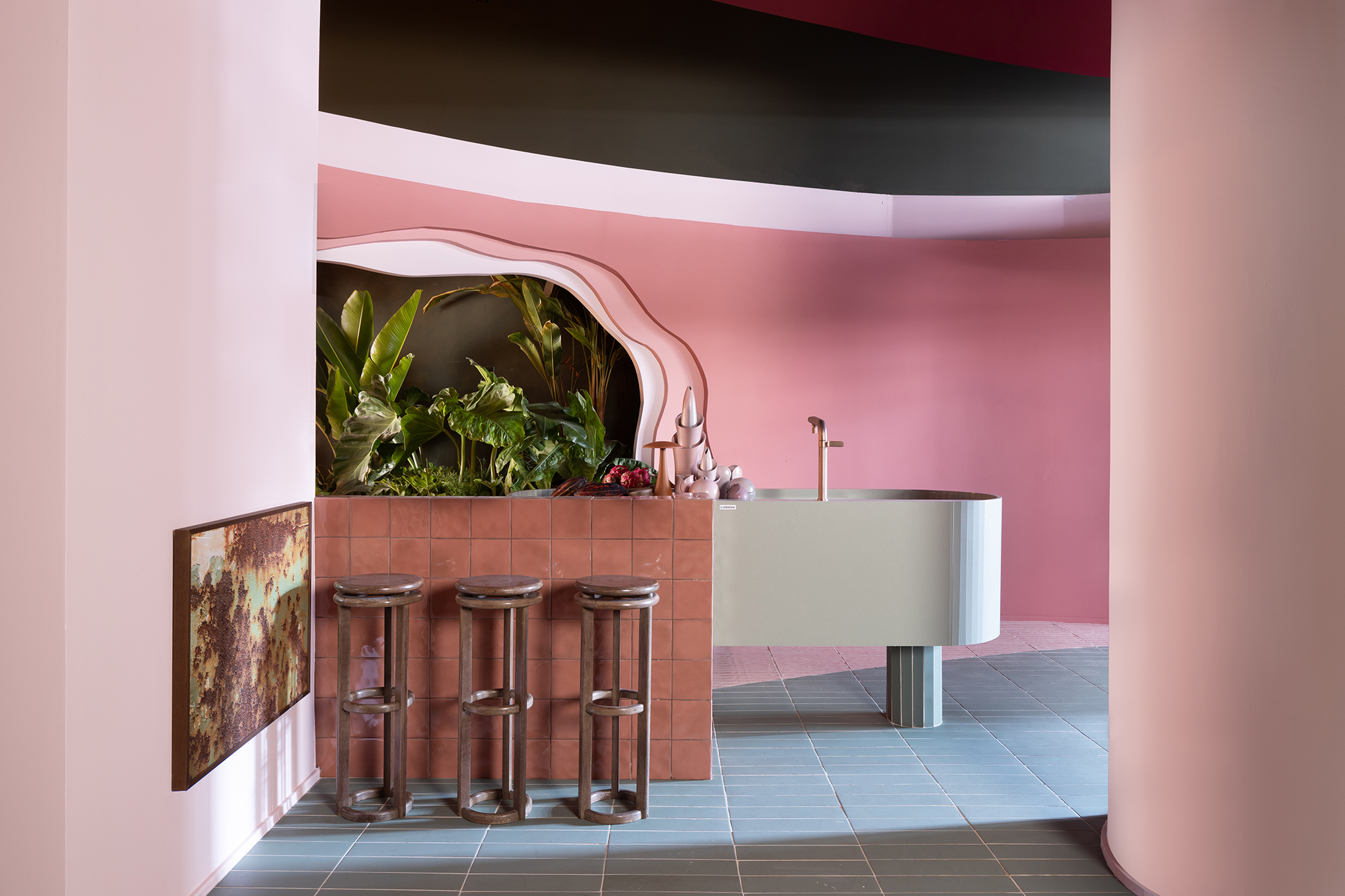 Casa rosa de 225 m² com cara de brinquedo feita para moradora de 64 anos. Projeto de Ricardo Abreu para a CASACOR SP 2023. Na foto, cozinha com bancada curva e paredes rosa.