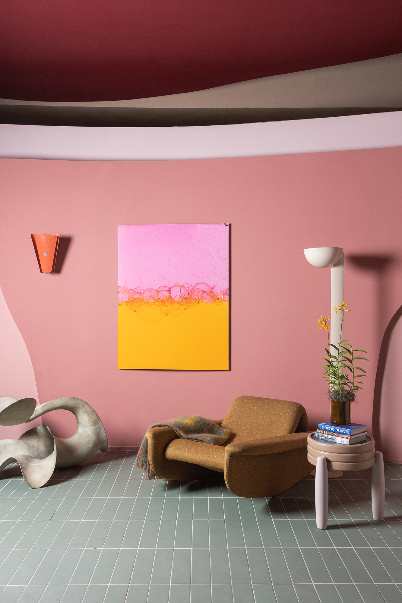Casa rosa de 225 m² com cara de brinquedo feita para moradora de 64 anos. Projeto de Ricardo Abreu para a CASACOR SP 2023. Na foto, sala com parede rosa e poltrona.