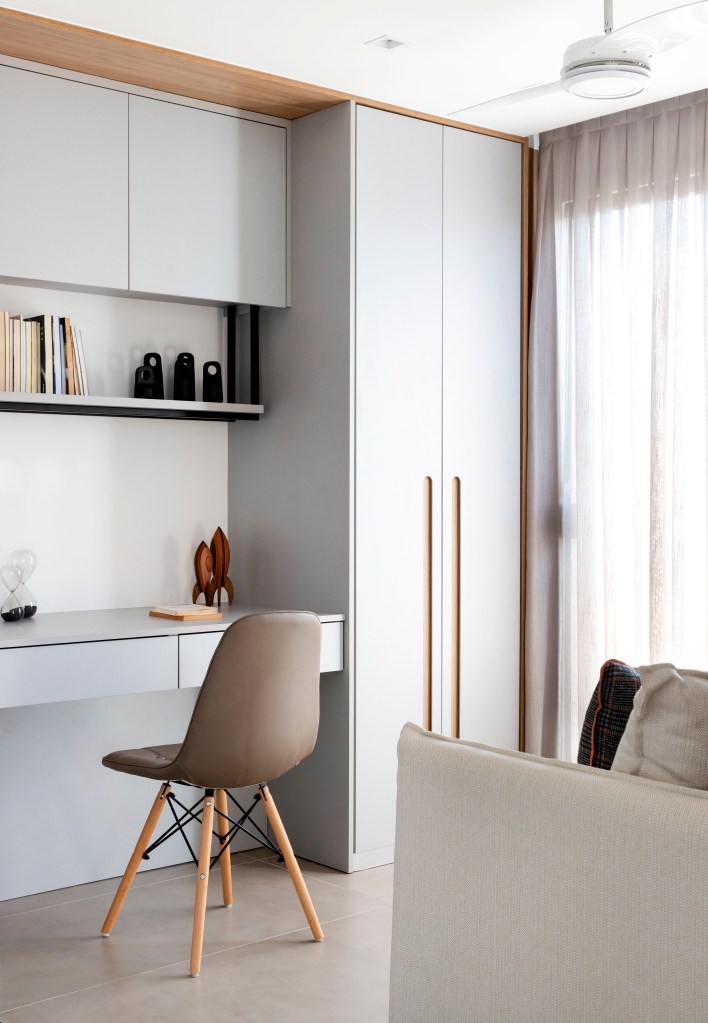 Home office claro, clean com marcenaria cinza clara e cadeira Eames marrom.