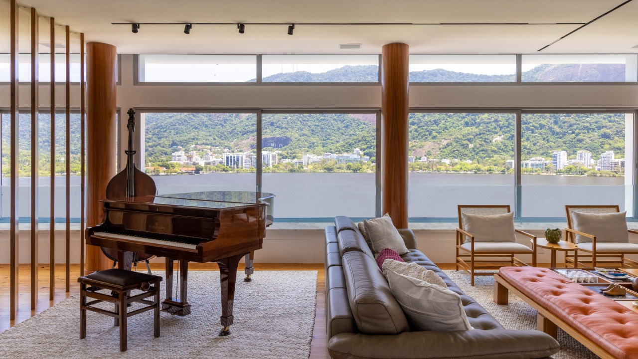 Cobertura triplex possui entrada privativa da rua e estúdio de música. Projeto de Mauricio Nobrega. Na foto, sala com piano, vista para o mar e sofá.;