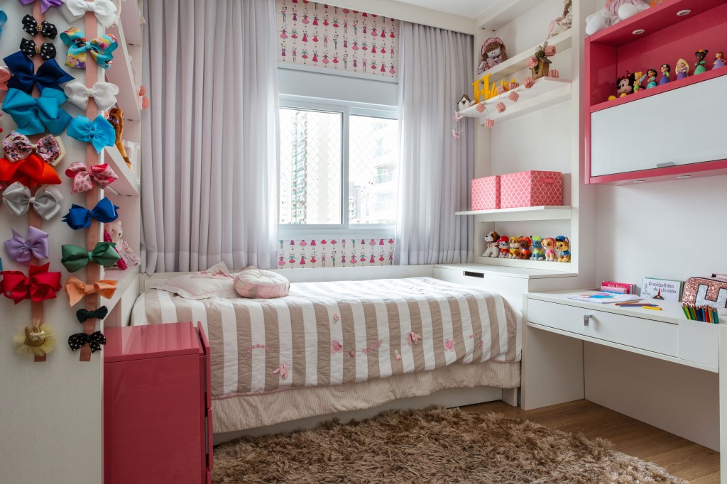 Quarto infantil com cama de solteiro, papel de parede e prateleiras com brinquedos.