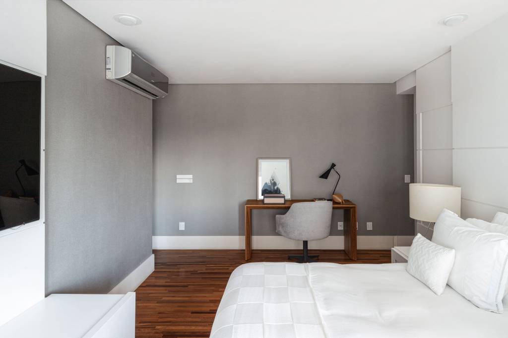 Quarto com cama de casal, piso de madeira, paredes cinzas e home office