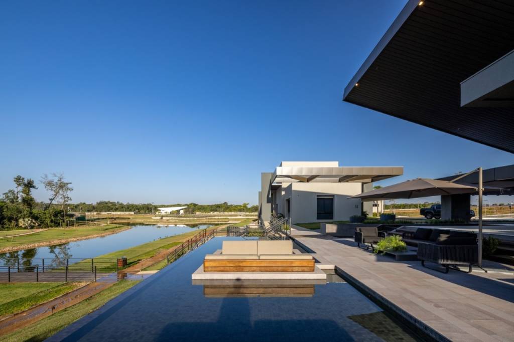 Condomínio em Mato Grosso rodeado pela mata nativa possui lago de 11 mil m². Projeto Truvian Arquitetura. Na foto, fachada da casa com piscina e jardim.