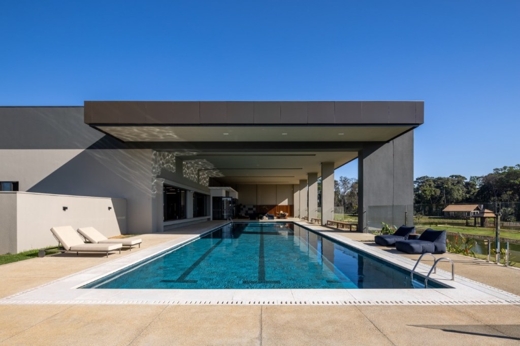 Condomínio em Mato Grosso rodeado pela mata nativa possui lago de 11 mil m². Projeto Truvian Arquitetura. Na foto, fachada da casa com piscina e jardim.