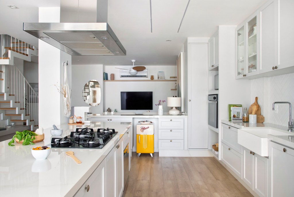 Cozinha branca clássica com piso de porcelanato padrão madeira.