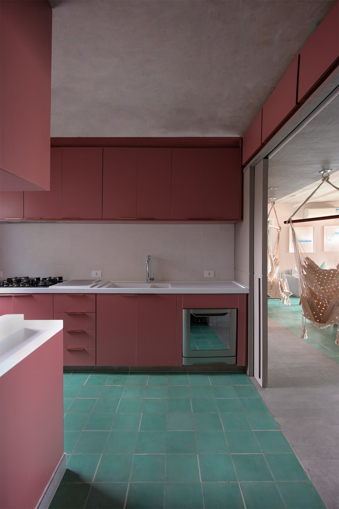 Ladrilho hidráulico cria unidade visual neste apartamento de 140 m². Projeto do Studio MEMM. Na foto, cozinha com piso verde de ladrilho hidráulico e marcenaria rosa.