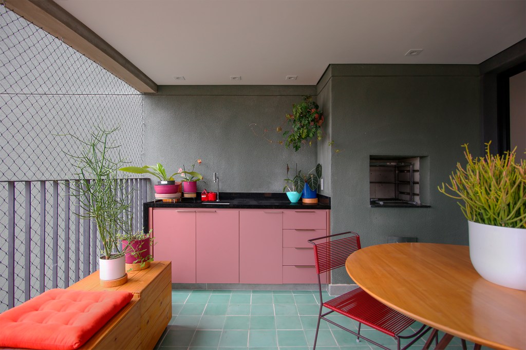 Ladrilho hidráulico cria unidade visual neste apartamento de 140 m². Projeto do Studio MEMM. Na foto, varanda com marcenaria rosa e churrasqueira.