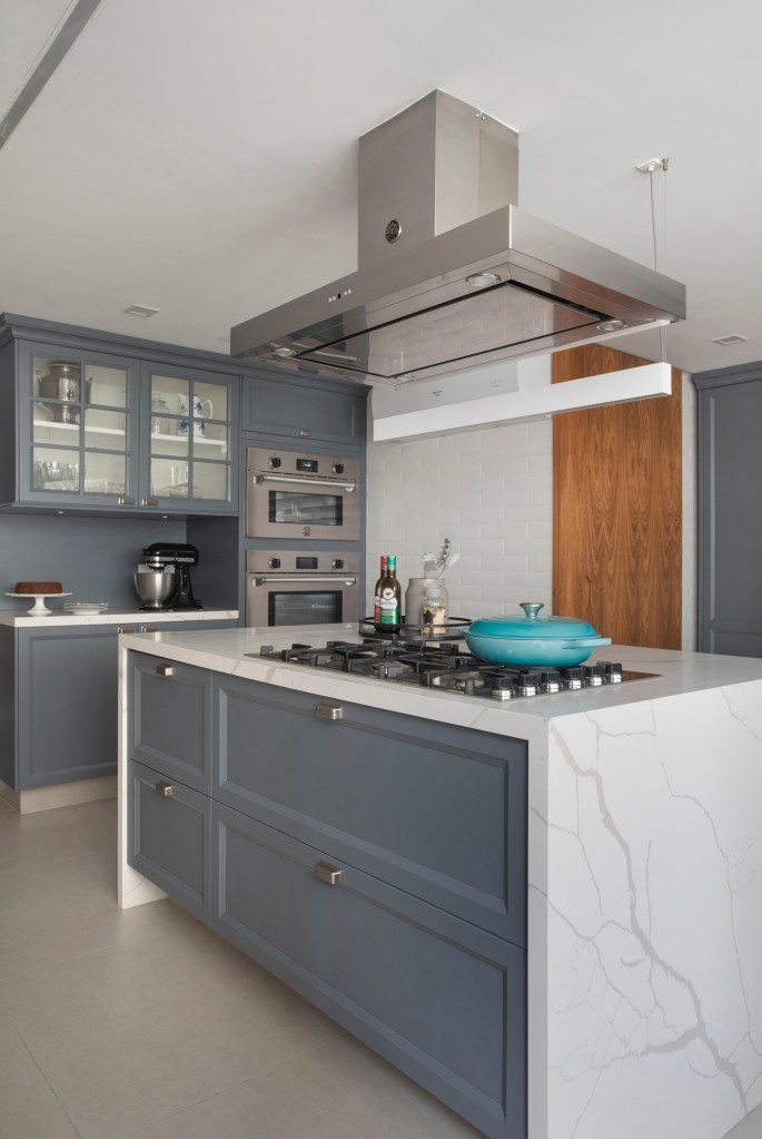 Cozinha com marcenaria cinza azulada e ilha com revestimento marmorizado.