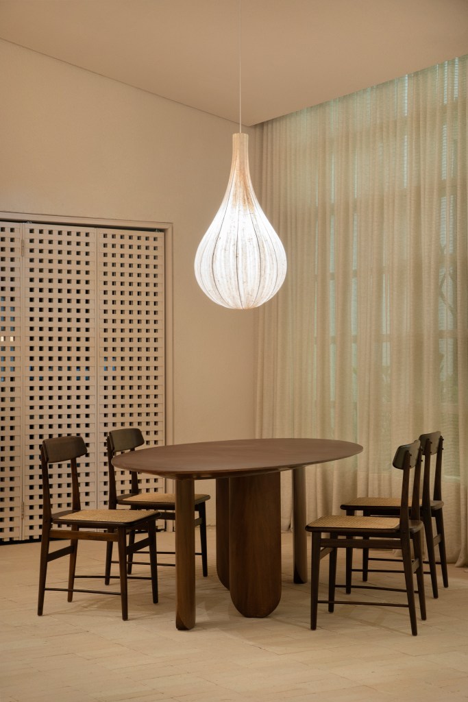 Loft de 120 m² é inspirado no caramujo aruá-do-mato. Projeto de Très Arquitetura para a CASACOR SP 2023. Na foto, sala de jantar com luminária de tecido e mesa de madeira.
