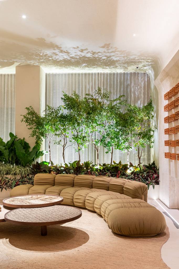 Marcas do tempo e histórias marcam o décor deste loft. Projeto de SUITE Arquitetos para a CASACOR SP 2023. Na foto, sala com sofá curvo e jardim.