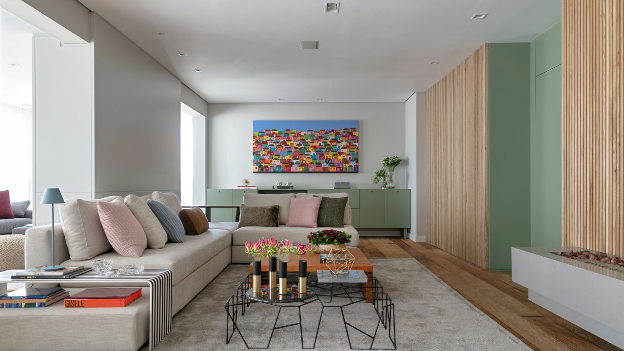 Sala de estar com tapete cinza claro, mesa de centro, sofá claro e aparador suspenso verde pistache.