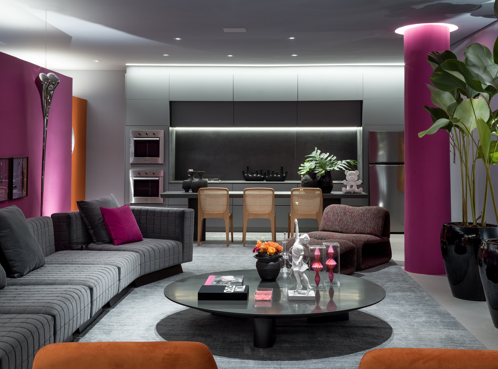 Sala integrada com cozinha; sofá cinza, tapete cinza, poltronas laranjas e marcenaria cinza.
