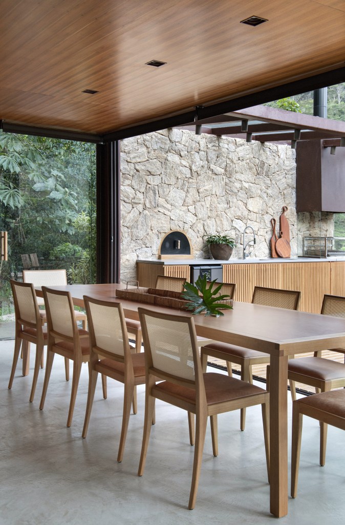 Sala de jantar com parede ripada de madeira e mesa de jantar de madeira grande.