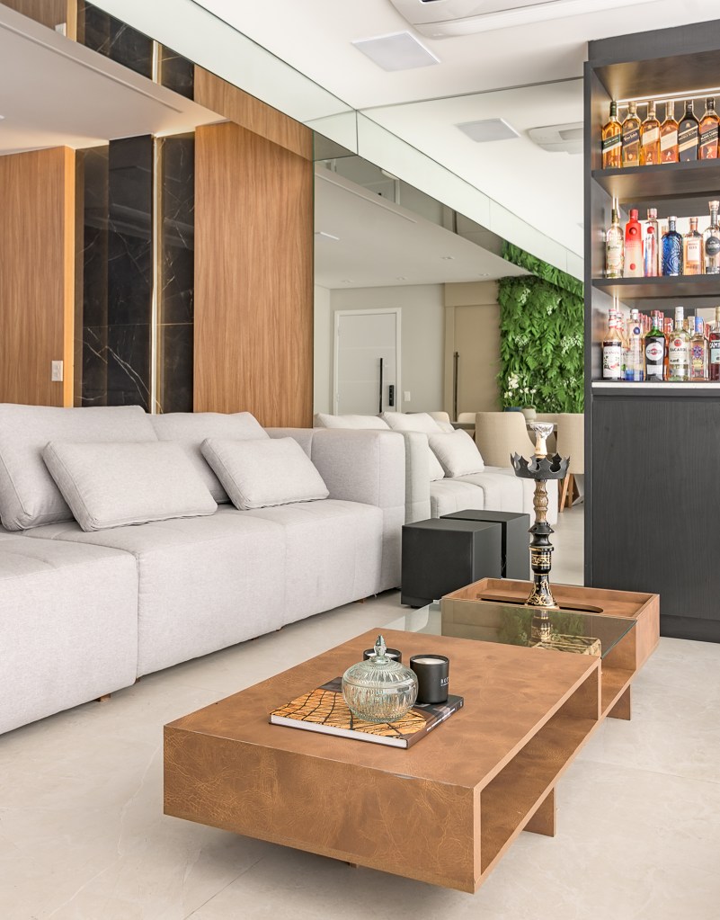 paineis-porcelanato-jardim-vertical-paredes-ape-134-m2-bianca-bahlis-credito-luiz-franco (1) Paineis de porcelanato e jardim vertical revestem paredes em apê de 134 m². Projeto de Bianca Bahlis. Na foto, sala de estar com bar, parede espelhada e poltronas.