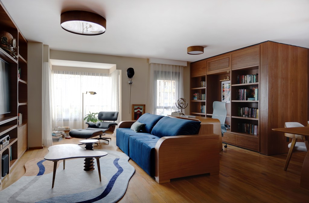 Peças retrôs e décor futurista se encontram no apartamento de 90 m². Projeto Trees Arquitetura. Na foto, sala de estar com home office, tv e móveis de madeira.